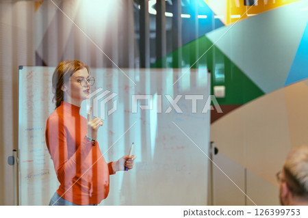 A pregnant business woman with orange hair confidently presents her business plan to colleagues in a modern glass office, embodying entrepreneurship and innovation A pregnant business woman with orange hair confidently presents her business plan to colleagues in a modern glass office, embodying entrepreneurship and innovation 126399753