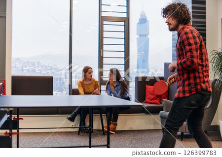 Business colleagues take a break from work to enjoy a game of table tennis, fostering teamwork and camaraderie in the workplace 126399783