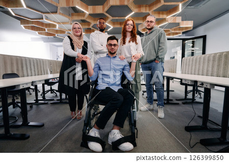 Young businessmen in a modern office extend a handshake to their business colleague in a wheelchair, showcasing inclusivity, support, and unity in the corporate environment. 126399850