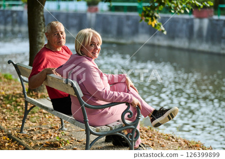 Elderly couple finding solace and joy as they rest on a park bench, engaged in heartfelt conversation, following a rejuvenating strol a testament to the enduring companionship and serene connection 126399899
