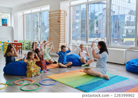 Reading time in an elementary school or kindergarten, a teacher reads a book to children in an elementary school or kindergarten. The concept of pre-school education. Selective focus 126399902