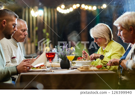 A group of family friends, comprising a young grandson and older individuals, share a delightful dinner in a modern restaurant, exemplifying the concept of healthy aging through intergenerational A group of family friends, comprising a young grandson and older individuals, share a delightful dinner in a modern restaurant, exemplifying the concept of healthy aging through intergenerational 126399940