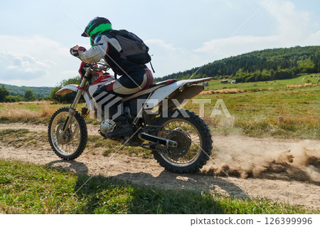 A professional motocross rider exhilaratingly riding a treacherous off-road forest trail on their motorcycle. A professional motocross rider exhilaratingly riding a treacherous off-road forest trail on their motorcycle. 126399996