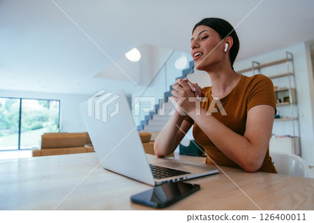 Woman sitting in living room using laptop looking at cam talk by video call with business friend relatives, head shot. Job interview answering questions 126400011