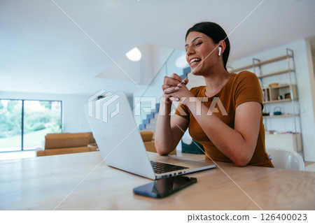 Woman sitting in living room using laptop looking at cam talk by video call with business friend relatives, head shot. Job interview answering questions 126400023