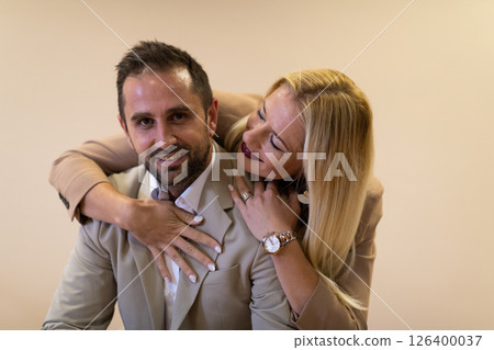 A business couple posing for a photograph together against a beige backdrop, capturing their professional partnership and creating a timeless image of unity and success. A business couple posing for a photograph together against a beige backdrop, capturing their professional partnership and creating a timeless image of unity and success. 126400037