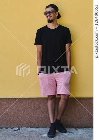 Middle Eastern Teenager Leaning Against Yellow Wall in Casual Attire Middle Eastern Teenager Leaning Against Yellow Wall in Casual Attire 126400053