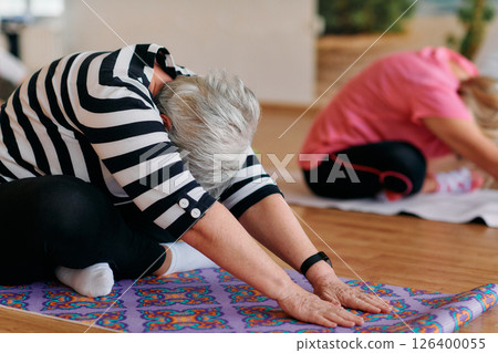 Senior Women Embrace Wellness: Yoga and Stretching in a Sunlit Space 126400055