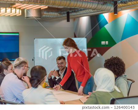 A diverse team of business experts in a modern glass office, attentively listening to a colleague's presentation, fostering collaboration and innovation A diverse team of business experts in a modern glass office, attentively listening to a colleague's presentation, fostering collaboration and innovation 126400143