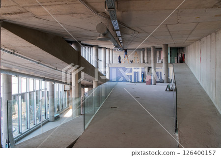 A captivating view of a modern business building under construction, showcasing its raw industrial interior with exposed steel beams and concrete walls bathed in the warm, golden hues of a sunset 126400157