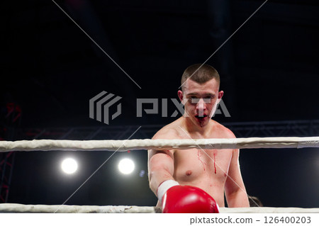 A bloodied boxer basks in the glory of victory, saluting the crowd after a grueling fight. A bloodied boxer basks in the glory of victory, saluting the crowd after a grueling fight. 126400203