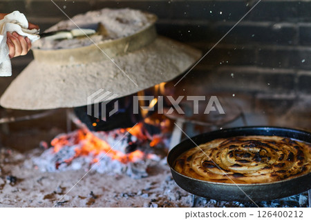 Capturing the essence of Bosnian culinary tradition, step-by-step preparation of a traditional Bosnian pie, showcasing the meticulous craftsmanship and authentic flavors involved in the culinary 126400212