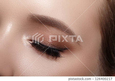 Elegance close-up of female eye with classic dark brown smoky make-up. Macro shot of woman's face part. Beauty, cosmetics and makeup. Elegance close-up of female eye with classic dark brown smoky make-up. Macro shot of woman's face part. Beauty, cosmetics and makeup. 126400217