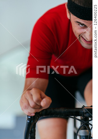 A triathlete riding a triathlon bike on a machine simulation in a modern living room. Training during pandemic conditions. 126400225