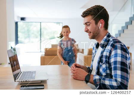 A freelancer sitting at a table in a modern living room, with headphones using a laptop for business video chat, conversation with friends and entertainment A freelancer sitting at a table in a modern living room, with headphones using a laptop for business video chat, conversation with friends and entertainment 126400257
