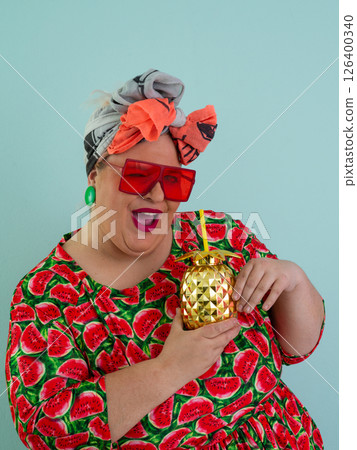 Playful Woman with Golden Pineapple Cup Wearing Watermelon Dress Playful Woman with Golden Pineapple Cup Wearing Watermelon Dress 126400340