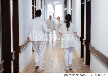 Medical personnel, including doctors and nurses, urgently respond in a busy hospital hallway, showcasing their quick action and teamwork in a critical situation 126400434