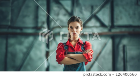 Confident and strong woman posing in a work uniform in a workshop.Generated image 126400560