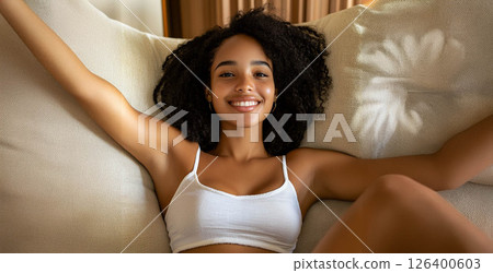 Young African woman with vitiligo smiling and relaxing on the sofa at home. Generated image 126400603