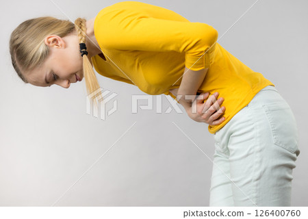 Woman feeling stomach cramps holding her belly Woman feeling stomach cramps holding her belly 126400760