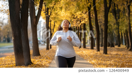 Tired African woman running outdoors in a city park on a crisp autumn morning with headphones on. Generated image 126400949