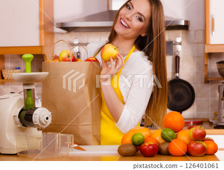 Woman in kitchen preparing fruits for juicing Woman in kitchen preparing fruits for juicing 126401061