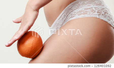 Girl holding orange next to leg 126401092