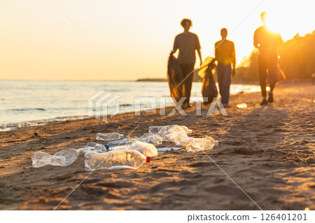 Earth day. Volunteers activists team collects garbage cleaning of beach coastal zone. Woman mans with trash in garbage bag on ocean shore. Environmental conservation coastal zone cleaning 126401201