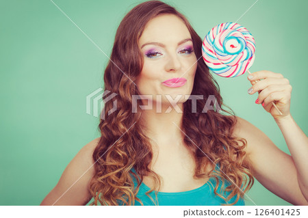 Smiling girl with lollipop candy on teal Smiling girl with lollipop candy on teal 126401425