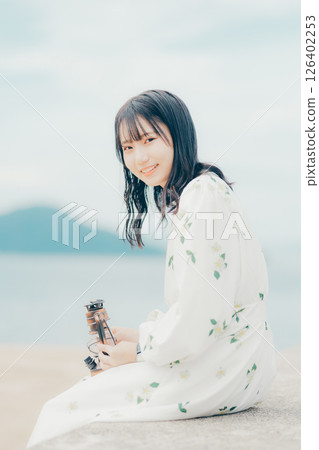 A woman and a lantern standing quietly on a calm beach 126402253
