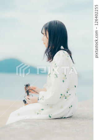 A woman and a lantern standing quietly on a calm beach 126402255