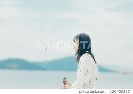 A woman and a lantern standing quietly on a calm beach A woman and a lantern standing quietly on a calm beach 126402257