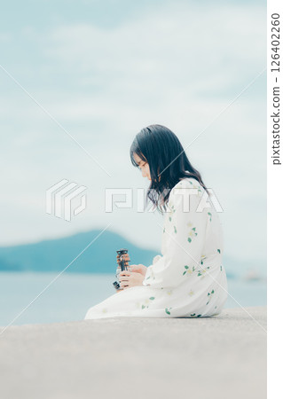 A woman and a lantern standing quietly on a calm beach A woman and a lantern standing quietly on a calm beach 126402260
