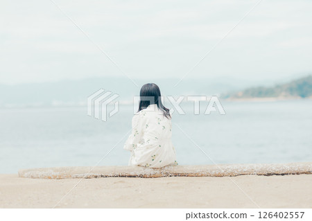 A woman in a floral dress looking at her smartphone on the beach A woman in a floral dress looking at her smartphone on the beach 126402557