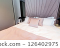 A cozy modern hotel bed with pastel pillows, elegant headboard and soft white bedding in a relaxing interior 126402975