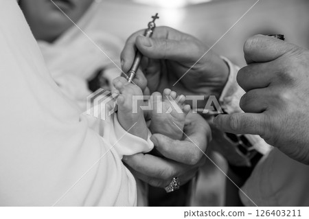A tender moment of a baby's baptism ceremony, capturing the hands of a priest pouring water over the infant's feet symbolizing spiritual cleansing and rebirth 126403211