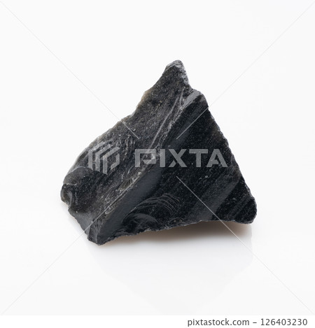Raw Obsidian Rock Specimen on White Background: A Dark Volcanic Glass Formation with Reflective Surface and Rough Texture Displayed in Studio Lighting 126403230