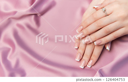Woman showing french manicure on pink satin background 126404753