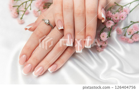 Woman showing french manicure and engagement ring on white satin background Woman showing french manicure and engagement ring on white satin background 126404756