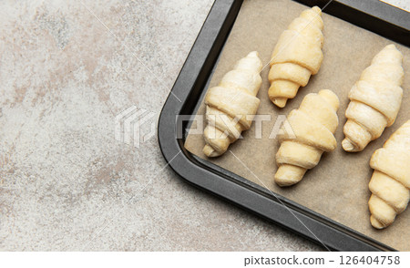 Raw croissants resting on baking sheet awaiting oven's warmth Raw croissants resting on baking sheet awaiting oven's warmth 126404758