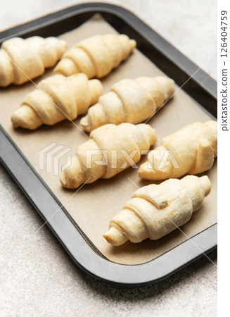 Raw croissants resting on baking sheet awaiting oven's warmth 126404759