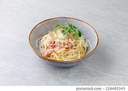 Creamy Pasta Carbonara with Bacon Parmesan and Pea Shoots in Ceramic Bowl 126405343