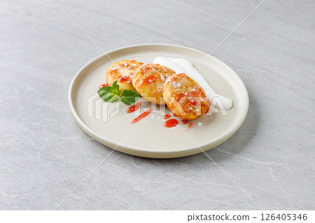 Cottage Cheese Pancakes Syrniki with Strawberry Sauce and Sour Cream on Beige Plate 126405346