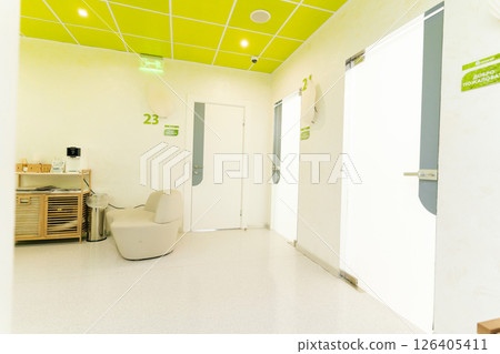 Empty waiting area of contemporary beauty clinic featuring comfortable sofa, coffee station and numbered doors leading to treatment rooms, all under vibrant green ceiling, no people, nobody. 126405411