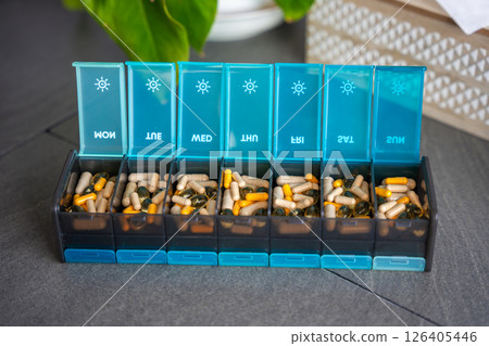 Weekly pill organizer with labeled compartments for daily medication doses. Concept of health management and medication planning 126405446