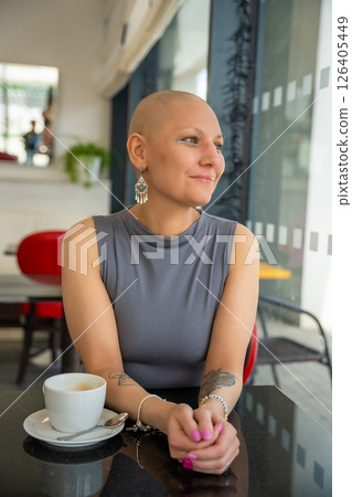 Confident young woman with cancer enjoying coffee in a cafe, embracing life despite illness. The concept shows that a cancer diagnosis does not take away the ability to enjoy normal activities 126405449