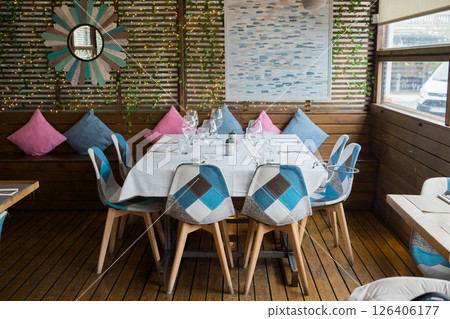 Cozy outdoor dining area with colorful cushions and wooden accents Cozy outdoor dining area with colorful cushions and wooden accents 126406177