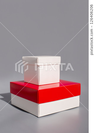 Stacked white and red gift boxes on gray background 126406206