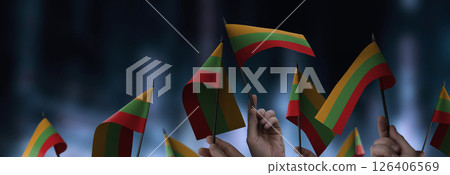 Lithuania flags in their hands on a blurred urban background 126406569