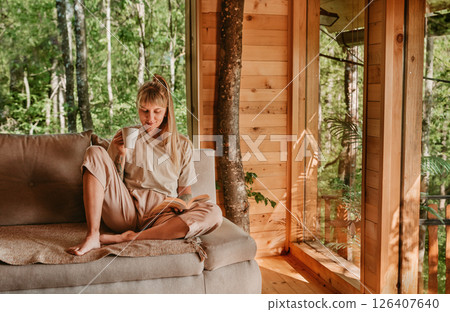 Woman Relaxing in Log Cabin with Tea and Book 126407640